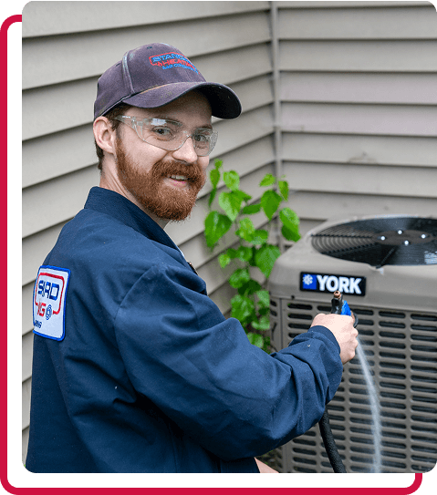 technician smiling while working on an AC unit